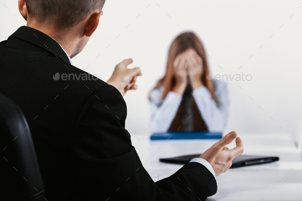 Depressed young woman during a conversation with the boss who points out her mistakes