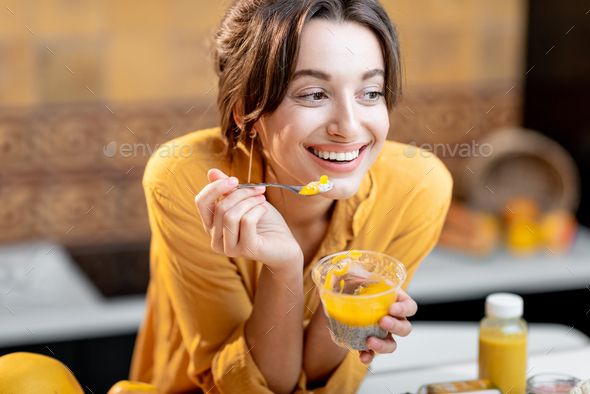 Woman eating chia pudding in the kitchen - Stock Photo - Images