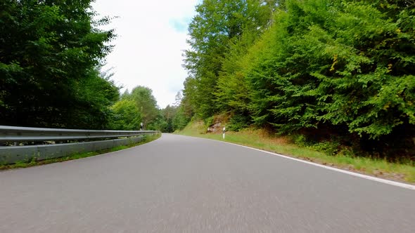 Car speeding on the road through forest in Germany