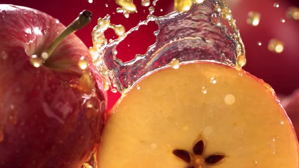 Slow Motion Shot of Red Apple Juice Splashing Through Apple Slices alt