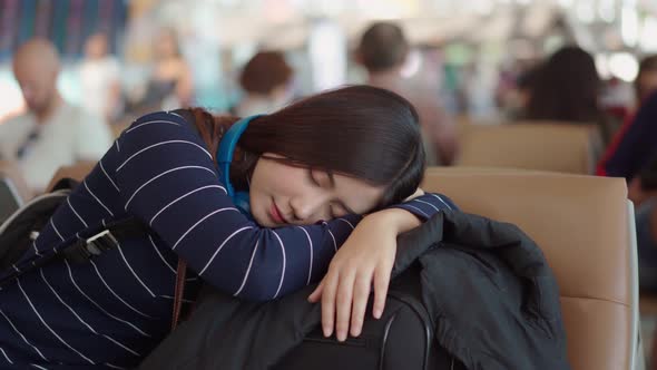 Female traveler sleeping in airport waiting delayed flight