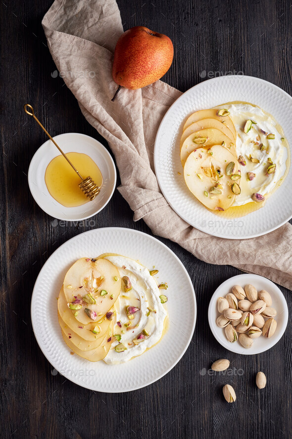 Ricotta with pears, pistachios and honey or maple syrup on two white plate on dark - Stock Photo - Images