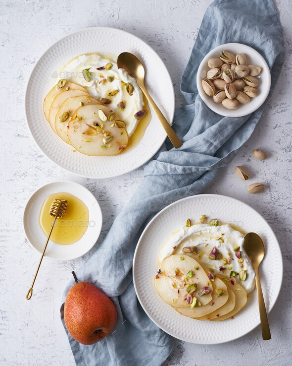 Ricotta with pears, pistachios and honey or maple syrup on white plate - Stock Photo - Images