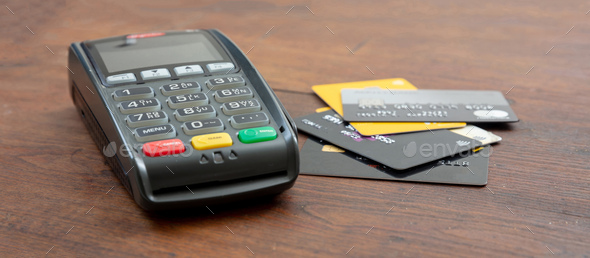 Payment machine, POS terminal and credit cards on wooden desk