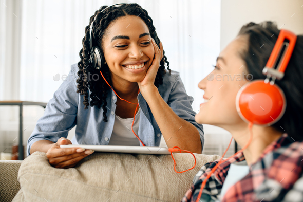Two happy women enjoys listening to music at home - Stock Photo - Images