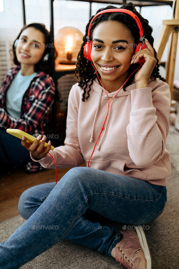 Women in headphones listening to music at home - Stock Photo - Images