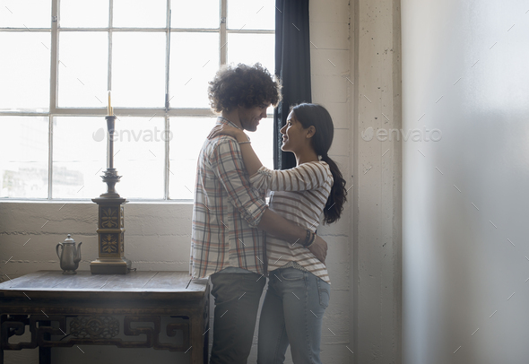 Loft living. A couple facing each other embracing.