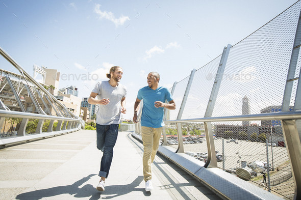 Two young men jogging along a bridge.