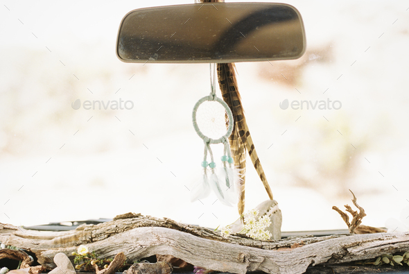 Close up of driftwood on a car dashboard, with accessories on rear view mirror. - Stock Photo - Images