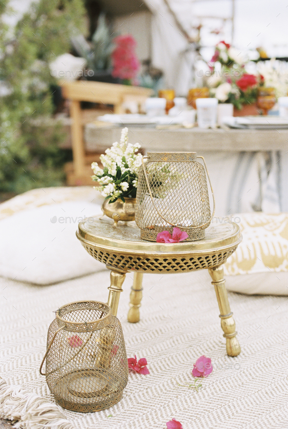 Lanterns and flowers on a small brass table outside a tent