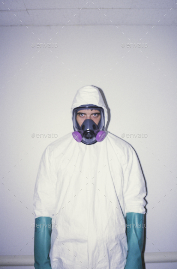 A man wearing a white protective clean suit and long thick blue gloves, and breathing mask.