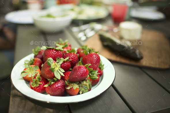 Picnic table with a meal laid out. A place of fresh strawberries. - Stock Photo - Images