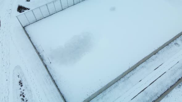 Flying over a sports field in a snow-covered city park. Aerial photography alt