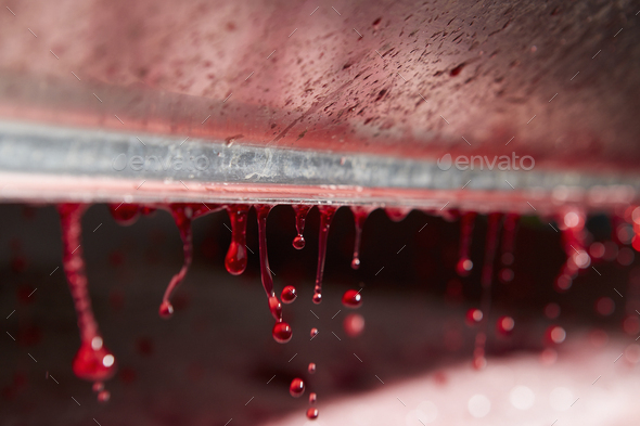 The interior of a grape press with droplets of fresh pressed juice dripping from a roller.