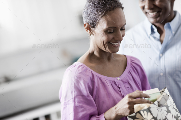 An affectionate mature African American couple, with their arms around each other in their home.