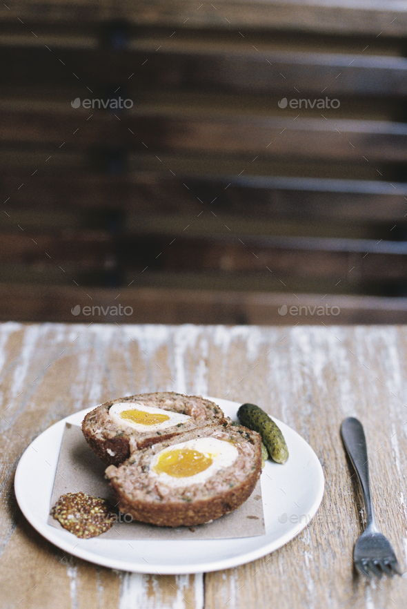A meal on a plate, a scotch egg cut in half with garnishes. - Stock Photo - Images