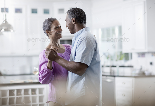 An affectionate mature African American couple, with their arms around each other dancing.