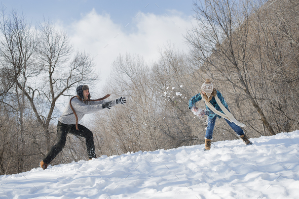 Winter scenery with snow on the ground. A couple having a snowball ...