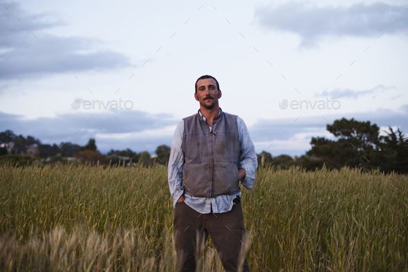 A man standing by a field of growing cereal crop at the Homeless