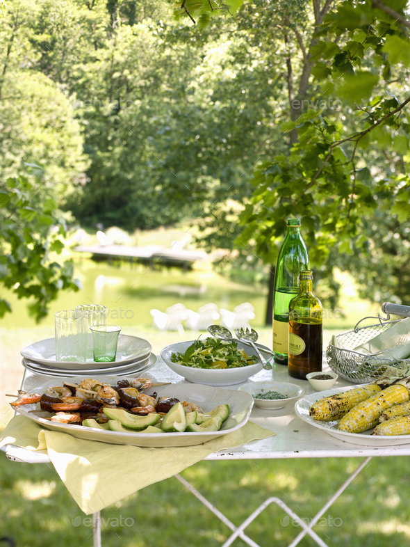 A buffet table set up in a garden for al al fresco meal. Salads and  prepared food dishes. Stock Photo by Mint_Images