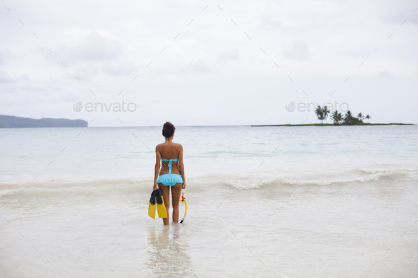 A young woman in shallow water with snorkeling gear on Samana Peninsula in the Dominican Republic.