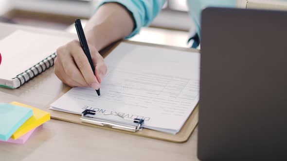 Close up man small business owner using a laptop and write checking parcel box. alt
