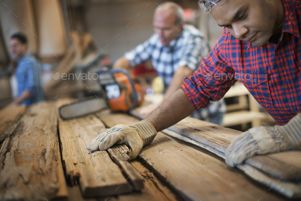 A man measuring and checking planks of wood for re-use and recycling.