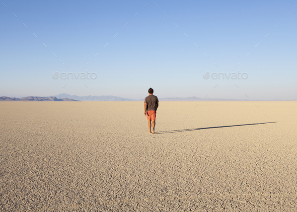 Man walking across a flat desert landscape
