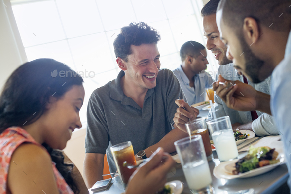 A group of men and women in a cafe, having drinks and enjoying each other\'s company.