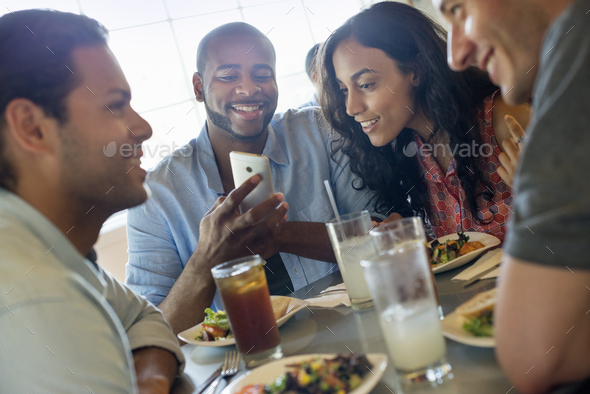 A group of men and women in a cafe, having drinks and enjoying each other\'s company.