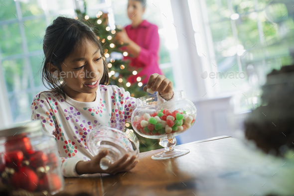 A young girl with a large glass jar of organic holiday gum drops. Decorations for Christmas.