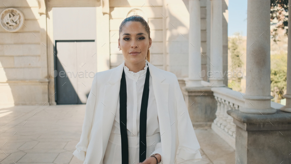 Posh elegant woman in white suit confidently walking along city park with old beautiful architecture - Stock Photo - Images