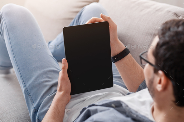 Reading books or blog and job search online. Man looks at tablet