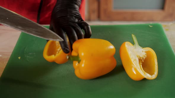 Close Up Cook Hands in Black Gloves Cut Yellow Bell Pepper with Knife alt