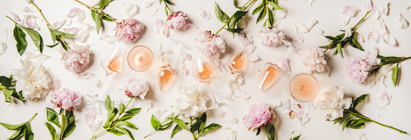 Variety of rose wine in glasses with flowers over plain white background
