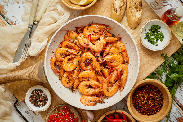 Roasted Prawns on frying pan served on white wooden cutting board - Stock Photo - Images