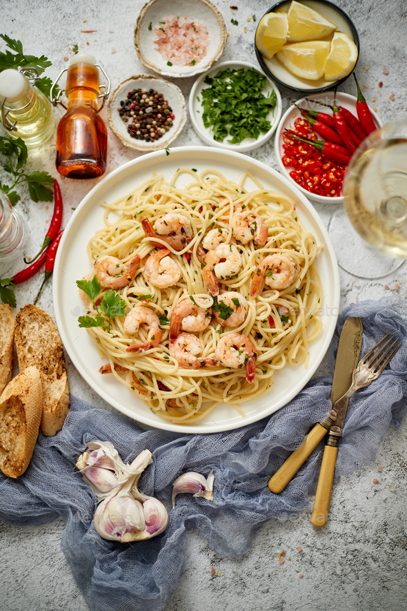Spaghetti with shrimps on white ceramic plate and served with glass of white wine - Stock Photo - Images