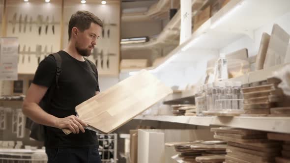 Buyer is Looking and Holding Big Cutting Board in Mall with Tableware Department alt