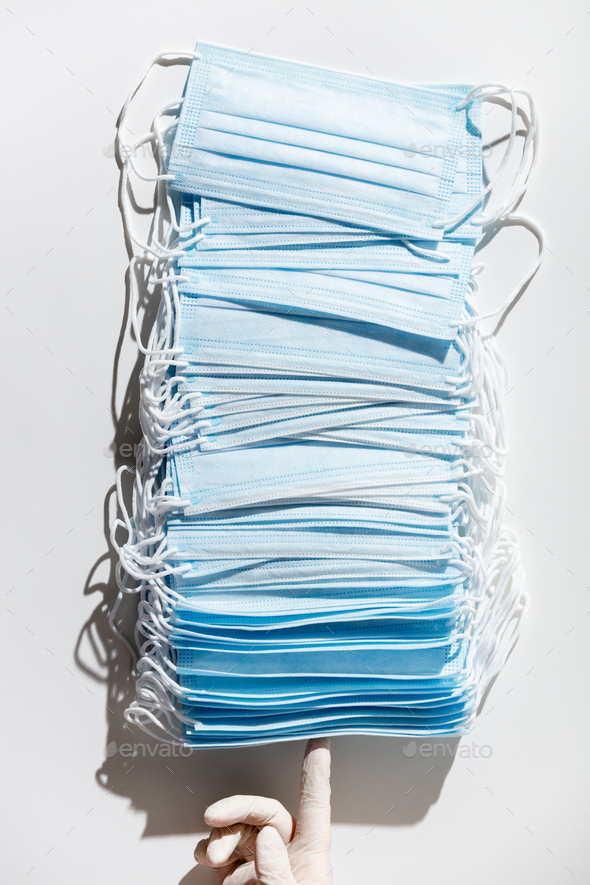 Woman hands in latex gloves holding a stack of facial medical masks, white background, close up - Stock Photo - Images