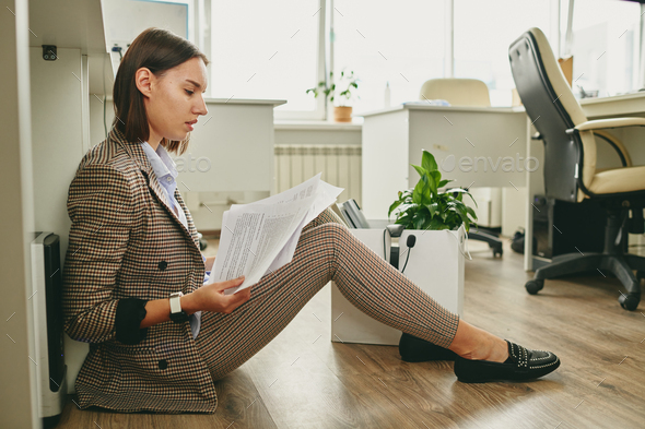 Young contemporary businesswoman in smart casualwear sitting on the floor