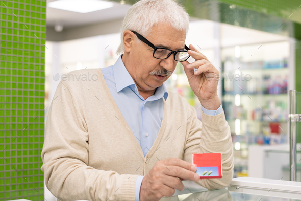 Senior man looking at package of new medicine or biologically active additives