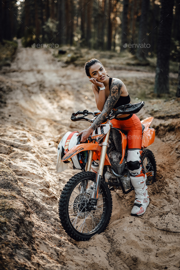 Female racer wearing motocross outfit with semi naked torso sitting on