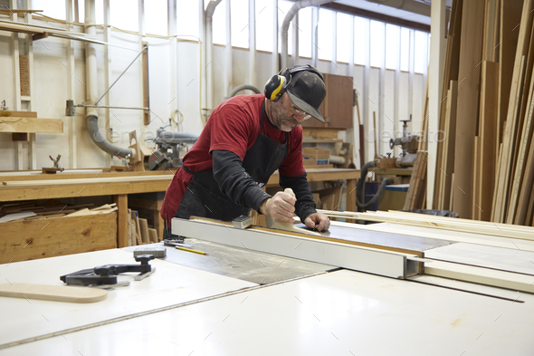 Carpenter using table saw in workshop