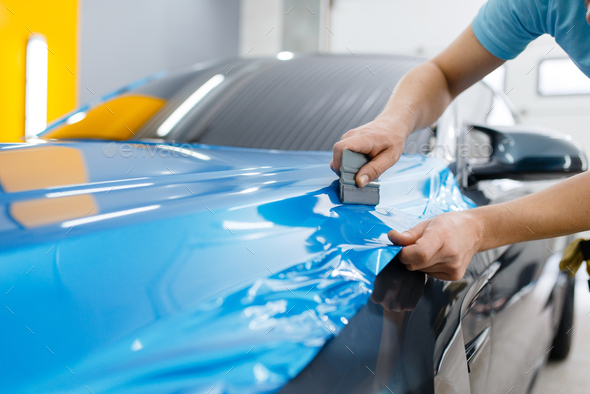 Car wrapping, mechanic with squeegee installs film - Stock Photo - Images