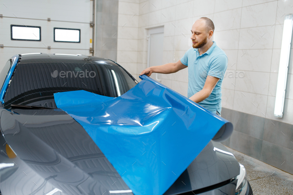 Car wrapper holds protective foil or film roll - Stock Photo - Images