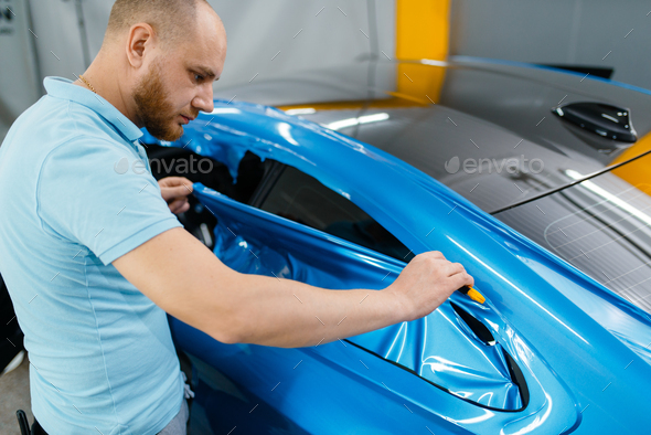 Car wrapping, mechanic cuts vinyl foil or film - Stock Photo - Images