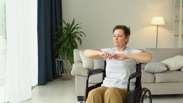 Mature 50 Yers Woman is Spreading Her Arms in Different Sides in Wheelchair alt