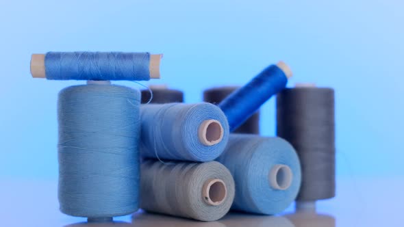 Sewing threads.Blue and gray thread spools on a light blue background. alt
