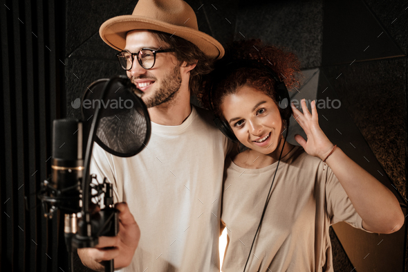 Portrait of young attractive musicians recording songs for new music album in sound studio