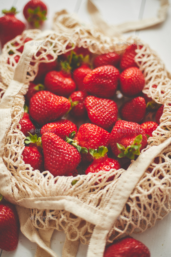 Fresh strawberries in eco-friendly package on white wooden background. Vegetarian organic meal - Stock Photo - Images
